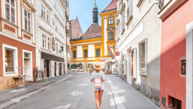 Junge asiatische Frau mit Rucksack und Hut zu Fuß auf der Stadtstraße in Europa.