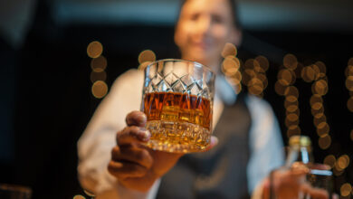 Barmitarbeiter*in hält ein Getränk © AEKACHAI LUNGMIN iStock Getty Images Plus