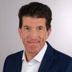 Foto von Frank Jost vor weißer Wand.