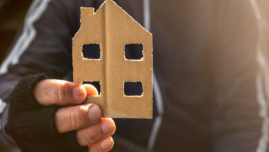 Obdachloser hält ein Haus aus Pappe in der Hand