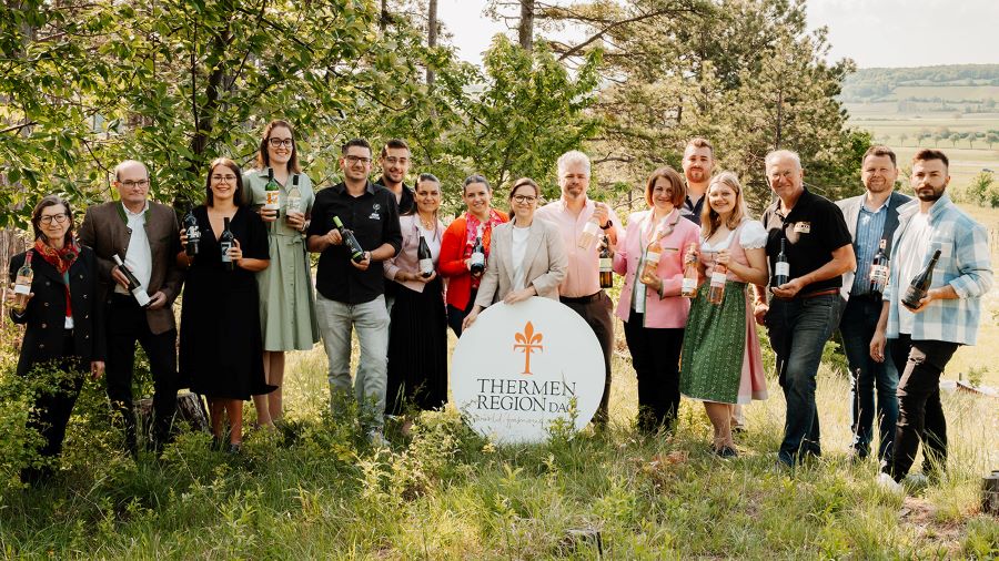 Eine Menschengruppe posiert für eine Pressefoto draußen.