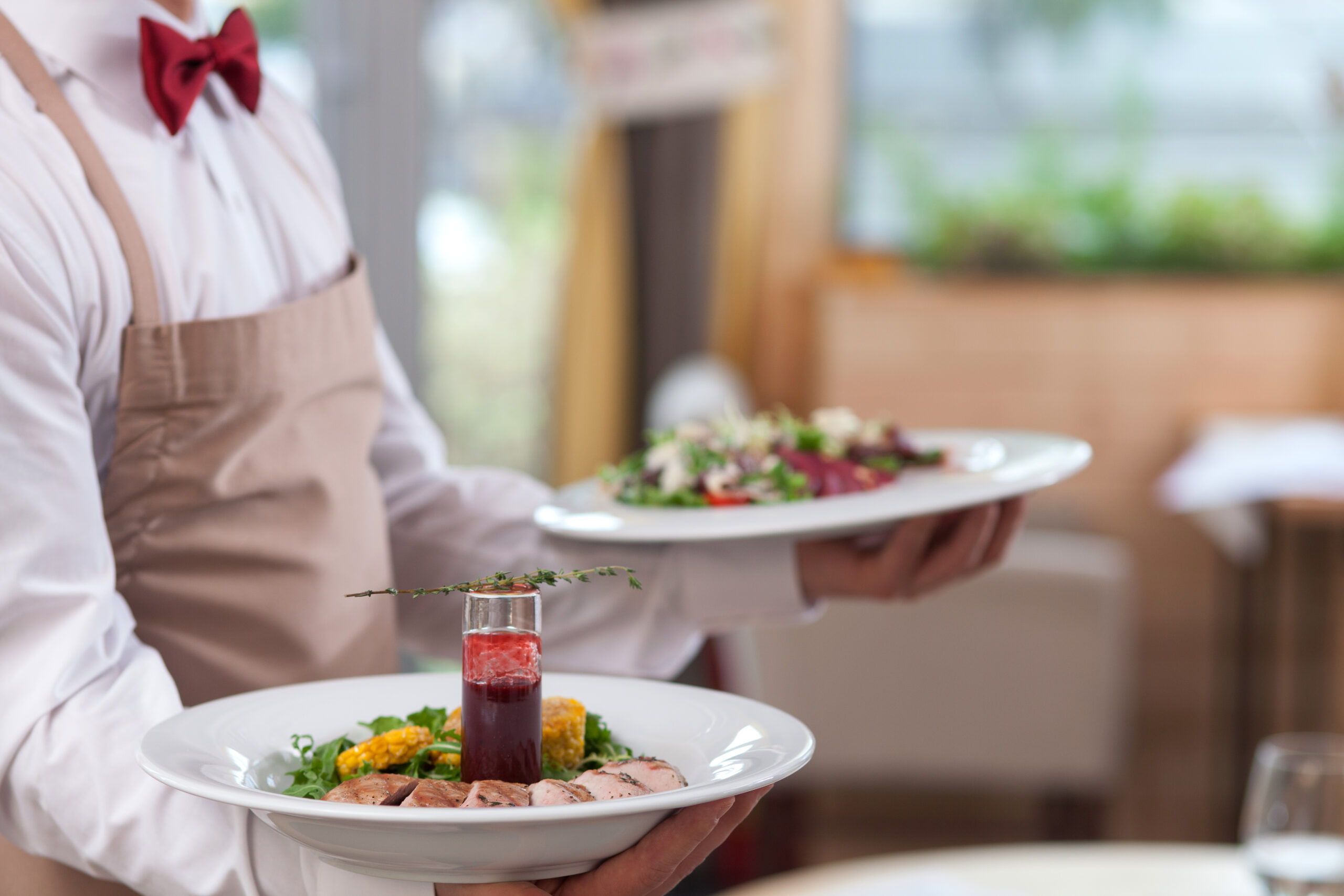 Kellner mit zwei Tellern © YakobchukOlena iStock Getty Images Plus