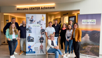 Eine Gruppe von Menschen posiert indoor vor einem Banner.