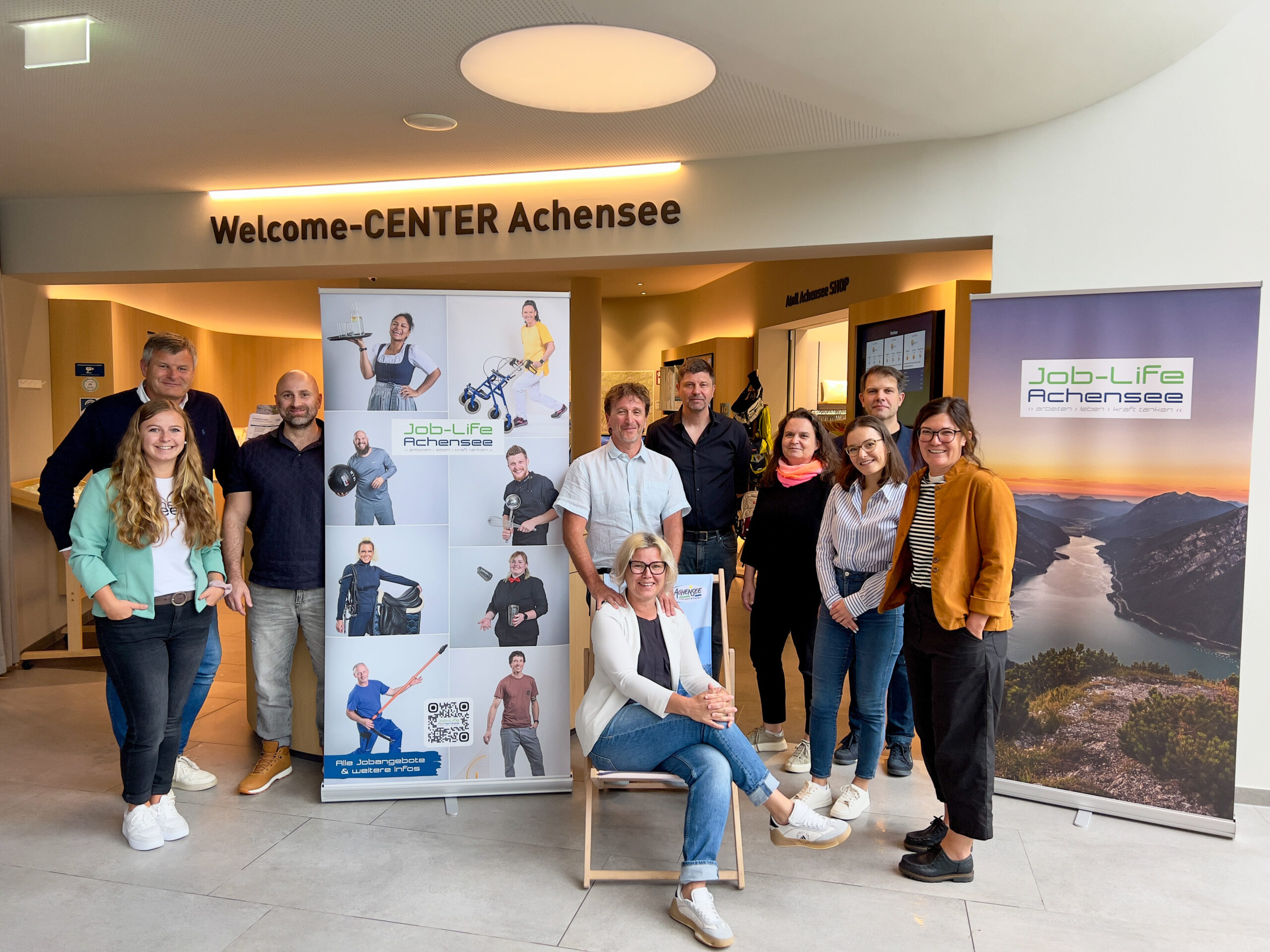 Eine Gruppe von Menschen posiert indoor vor einem Banner.