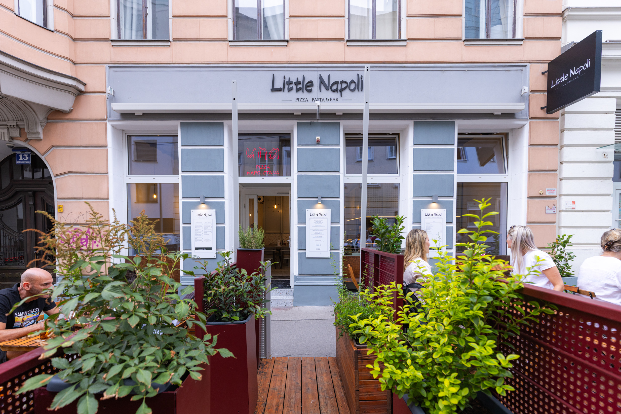 Fassade des neuen "Little Napoli" in Grau mit großzügigem Schanigarten davor.