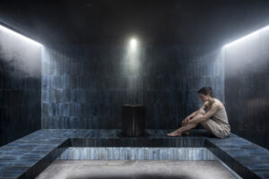 Almspa des Hotels: Eine Frau sitzt in einer Sauna.
