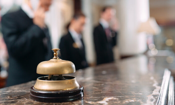 Eine Glocke steht im Vorderrund, ein Hotel Rezeptionsschalter im Hintergrund.