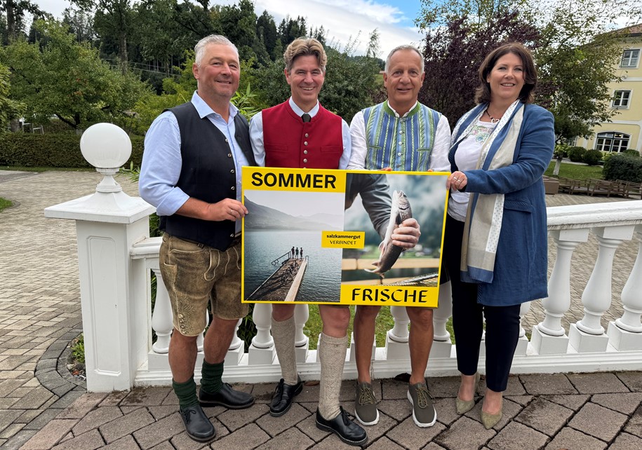 Vier Personen in Tracht halten ein Schild, das "Sommer Frische" sagt.